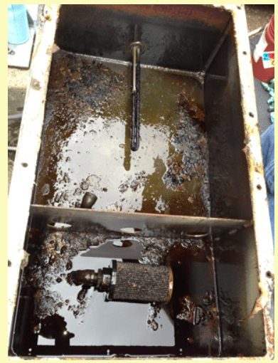 Rusty, contaminated tank with stagnant water and debris, highlighting potential maintenance issues