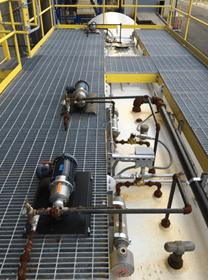 A view of a platform featuring industrial pumps, valves, and piping