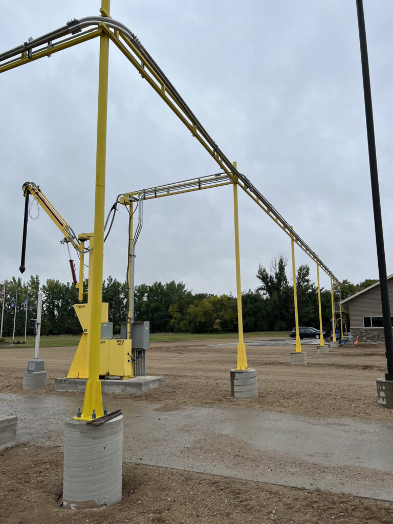 Yellow overhead piping system with support poles in an industrial area, designed for transporting materials
